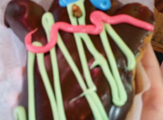 Voodoo Doughnut - Eugene, OR. Classic Voodoo doll donut. Complete with pretzel stick to stab doll and raspberry filling