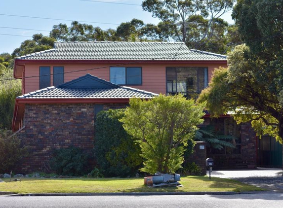 Total Roof Restoration - East Corrimal, NSW. Gable sealed as with tiles (Charcoal), roof restored, chimney junk in foreground being picked up.