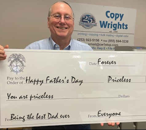 Copy Wrights Printing & Mailing - Fife, WA. Mark Coleman holding a whiteboard erasable check that Copy Wrights printed